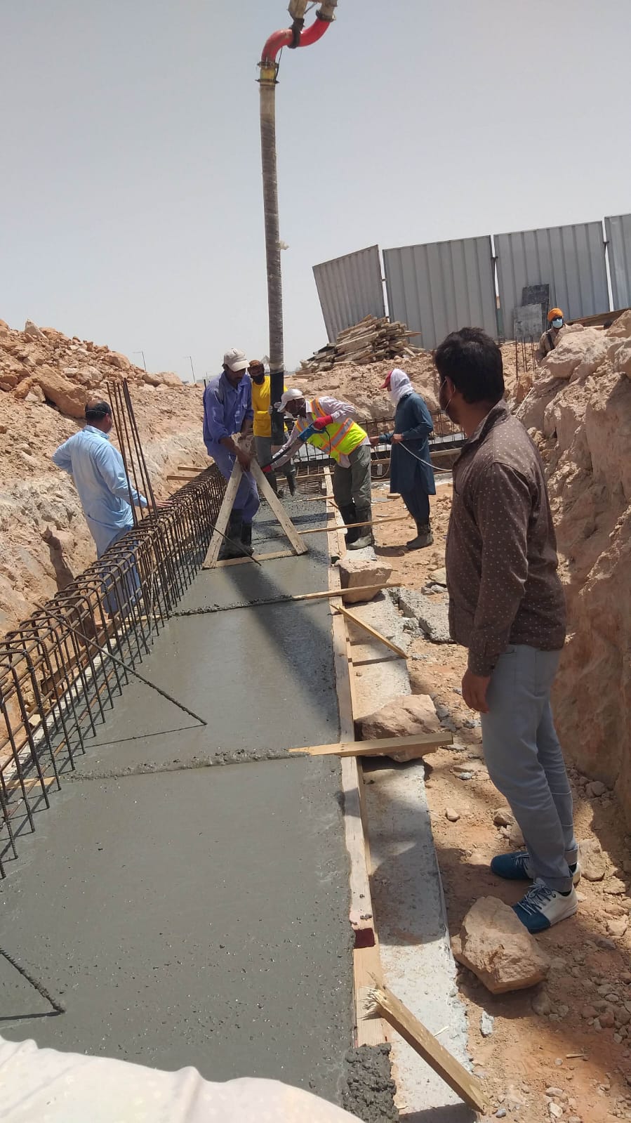 Crew pouring concrete into ground beam formwork, Shamkha South.