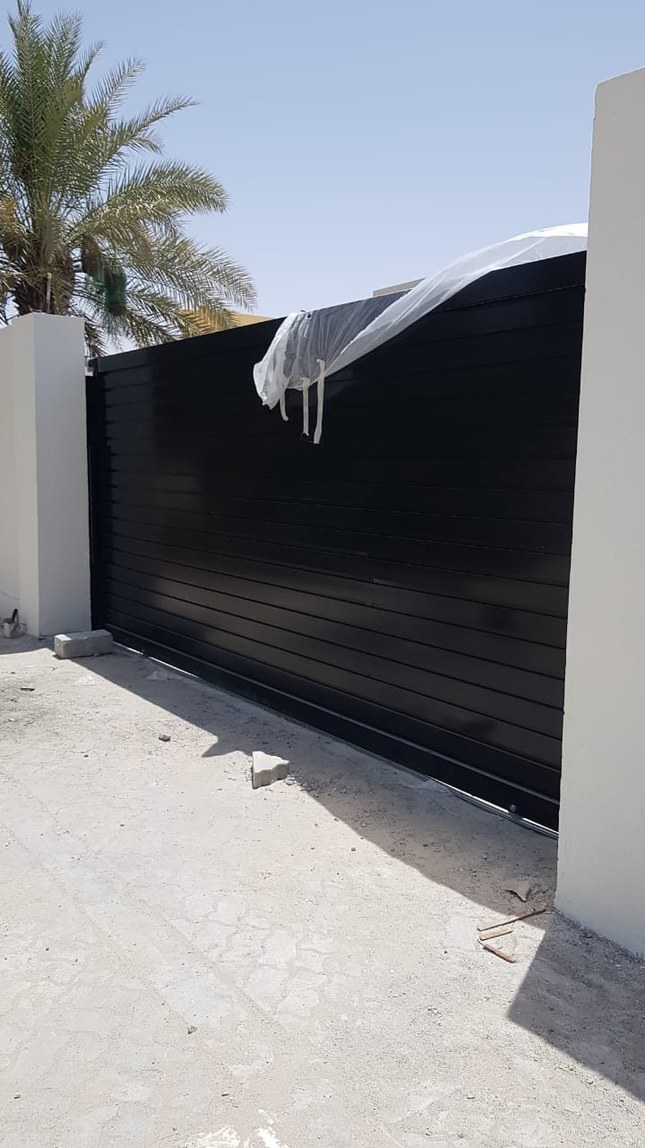 Black slatted sliding gate at a villa entrance