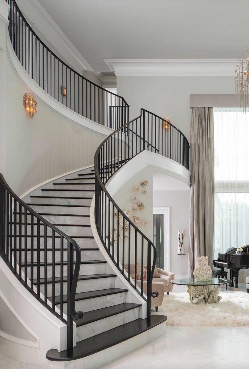 Sweeping curved marble staircase with iron balustrade.